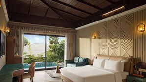 A spacious bedroom with a large bed, a desk, and a view of a swimming pool. - Debu's The Fern Resort & Spa Jim Corbett, Series by Marriott (Ramnagar)