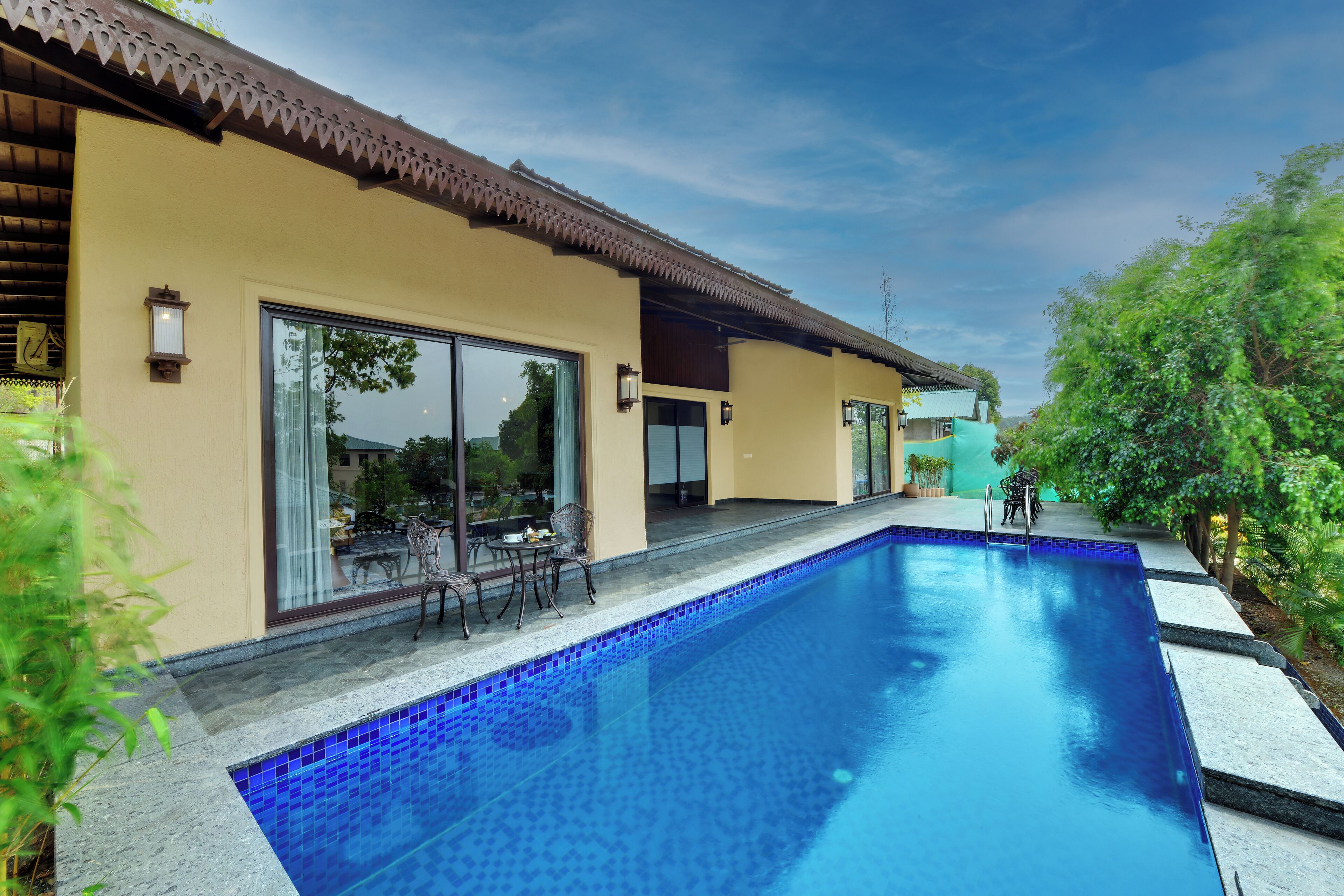 A modern house with a swimming pool, large sliding glass doors, and outdoor furniture.