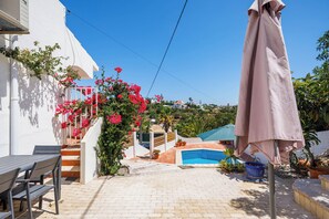Un patio con piscina, mobiliario exterior y plantas en macetas.