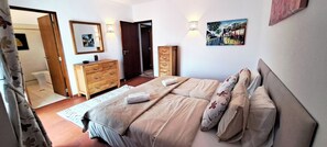 Un dormitorio con cama, cómoda, puerta y un cuadro en la pared.