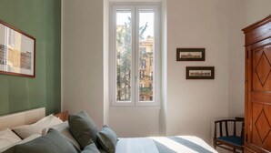 Une chambre à coucher avec un lit, des oreillers, une fenêtre et une armoire en bois.