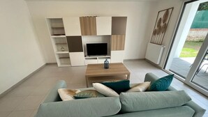 A modern living room with a sofa, a coffee table, and a flat-screen TV. - Cocon Neuf 6/8 pers à 2 pas des Plages, Port & Centre Ville (Saint-Pierre-Quiberon)