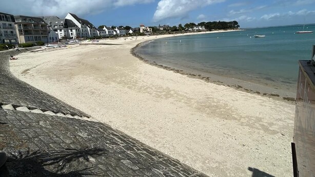 A beach with a curved shoreline, buildings in the background, and clear skies. - Cocon Neuf 6/8 pers à 2 pas des Plages, Port & Centre Ville (Saint-Pierre-Quiberon)