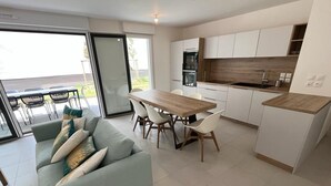 A modern kitchen with white cabinets, a wooden countertop, and a dining area with a table and chairs. - Cocon Neuf 6/8 pers à 2 pas des Plages, Port & Centre Ville (Saint-Pierre-Quiberon)