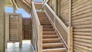 A wooden staircase with a metal railing, leading to an upper level. - The Salty Mermaid-Beachfront Views! Sleeps 8, 3 bedrooms,2 bathrooms. (Crystal Beach)