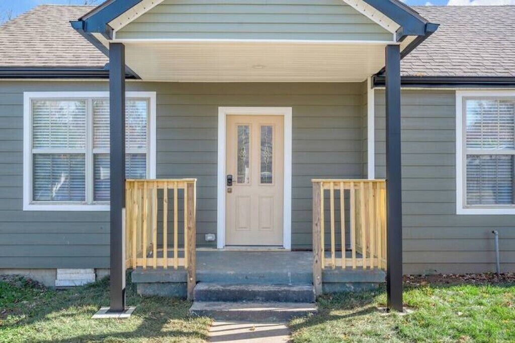 Una casa de dos pisos con un porche delantero, una puerta principal y dos ventanas.