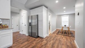 Eine moderne Küche mit weißen Schränken, einem Edelstahlkühlschrank und einem Essbereich mit Tisch und Stühlen.