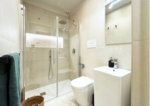 Een moderne badkamer met een douche met glazen wand, een wit toilet en een wastafel met spiegel erboven.