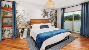 A bedroom with a bed, a hanging light fixture, a wall mural, and a window with curtains.