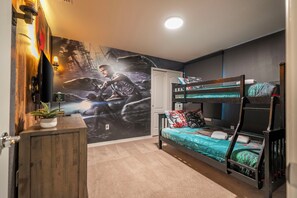 Quarto com beliches, um mural na parede, um armário de madeira e um vaso com planta.