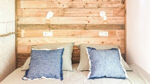 A bedroom with a wooden headboard, two bedside lamps, and a bed with striped bedding. - STOERbuiten Les Charmes (Saint-Andre-d'Allas)