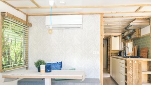A compact kitchen with wooden cabinetry, a built-in stove, and a window with blinds. - STOERbuiten Les Charmes (Saint-Andre-d'Allas)