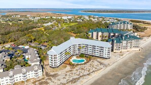 Ein Hotel an der Küste mit mehreren Gebäuden, einem Schwimmbad und direktem Strandzugang.