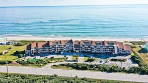 A multi-story hotel with a central courtyard, located near a beach with a clear view of the ocean. - Beachwalk 105, Oceanfront Condo in Pine Knoll Shores, NC! (Pine Knoll Shores)