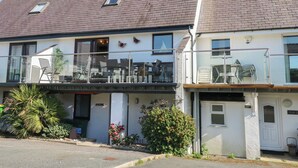 A two-story building with a balcony, a small window, and a door. - Hafan Bach - 233 Cae Du (Pwllheli)