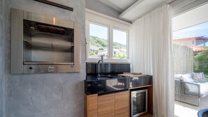 A modern kitchen with a built-in oven, a sink, and a window overlooking a balcony. - Bz77 Beachfront house with 4 suites! (Búzios)