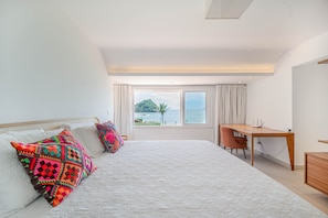 Un dormitorio con una cama grande, un escritorio y vistas al océano.