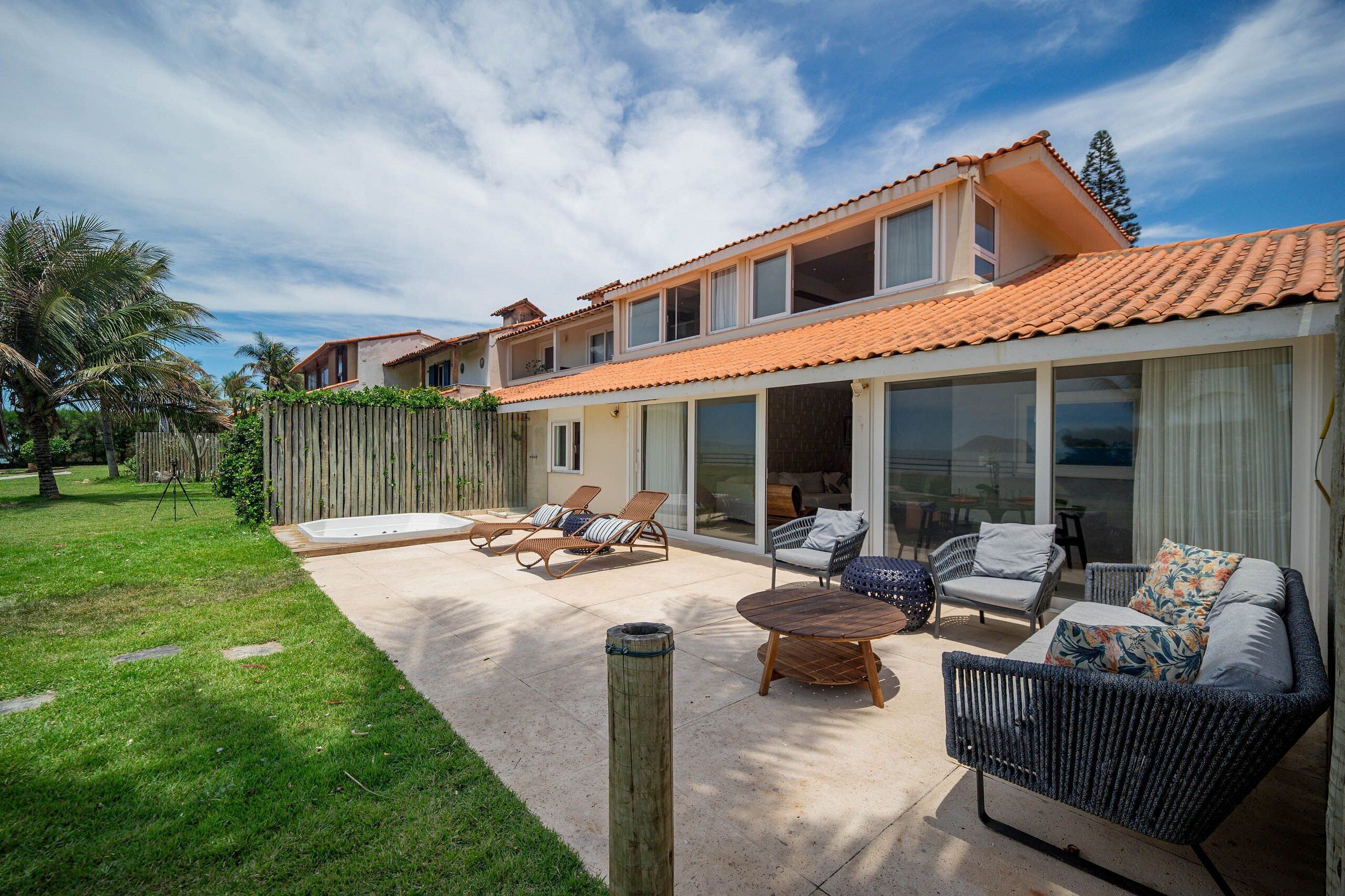 Une maison à deux étages dotée d’un patio aménagé avec du mobilier d’extérieur et une clôture en bois.
