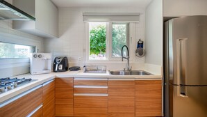 Una cocina moderna con armarios de madera, electrodomésticos de acero inoxidable y un ventanal que aporta luz natural.