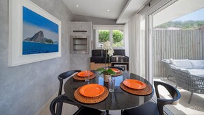 A dining area with a round table set for four, featuring orange plates and woven placemats. - Bz77 Beachfront house with 4 suites! (Búzios)