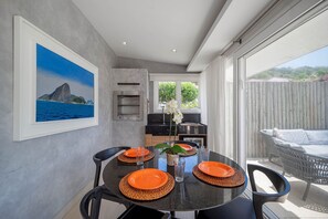 Comedor con una mesa redonda dispuesta para cuatro personas, con platos anaranjados y posavasos tejidos.