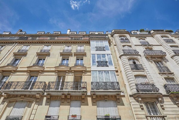 A multi-story building with classical architecture, featuring balconies with wrought iron railings and large windows.
