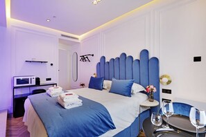 A modern hotel room with a large bed, a bedside table with a vase of flowers, and a small table with two glasses of water. - Suite with AC and jacuzzi Beaubourg Le Marais (Paris)