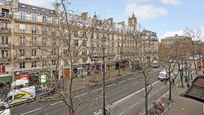 A street view with multi-story buildings, a pharmacy, and parked bicycles.