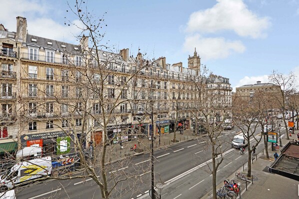 A street view with multi-story buildings, a pharmacy, and parked bicycles.