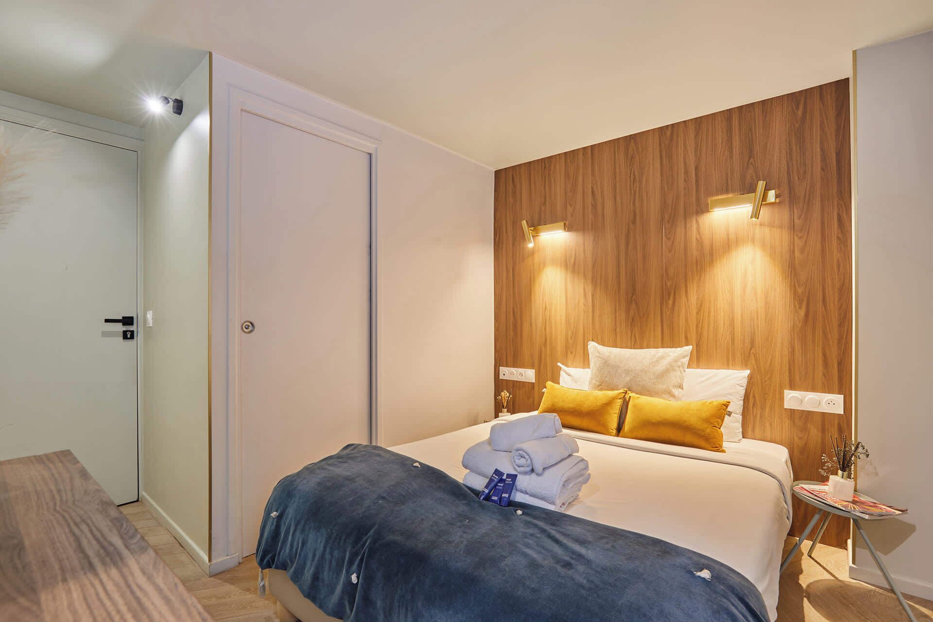 Ein Hotelzimmer mit Bett, Nachttisch und einer Wand mit Holzelementen.