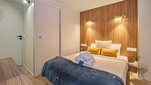 A hotel room with a bed, bedside table, and a wooden accent wall.