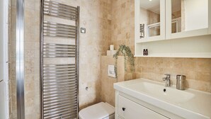 Une salle de bain avec un lavabo blanc, un miroir et un porte-serviettes.