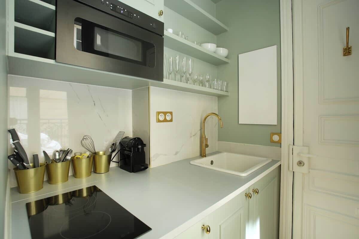 Une cuisine moderne dotée d’une plaque de cuisson à induction noire, d’un four en acier inoxydable et d’un robinet de couleur dorée.