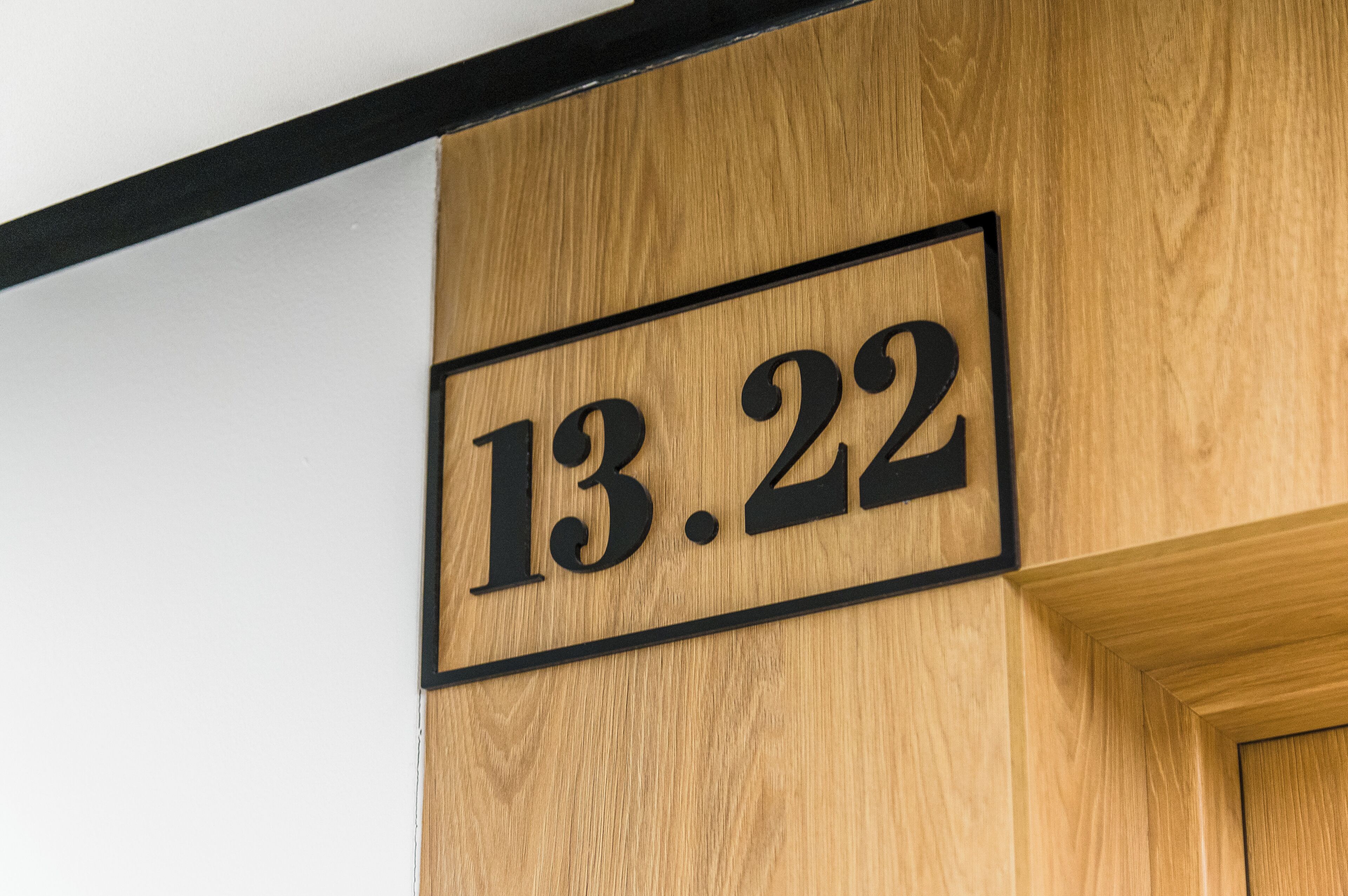 Una pared de madera con un letrero en marco negro que muestra el número 13.22.