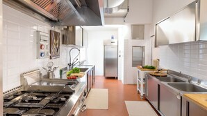 A modern kitchen with stainless steel appliances, white tiled walls, and a central island with fresh produce. - La Scuderia 8, Emma Villas (Savignano Sul Rubicone)