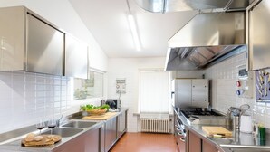 A modern kitchen with stainless steel appliances, a central island, and a window providing natural light. - La Scuderia 8, Emma Villas (Savignano Sul Rubicone)