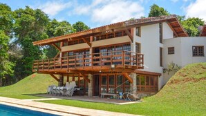 A two-story house with a balcony, a swimming pool, and a grassy yard.