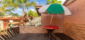 Relax on the patio surrounded by lush greenery and palm trees, with a shaded area and comfortable seating.