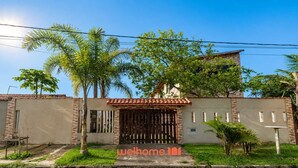 A residential property with a gated entrance, a tiled roof, and a well-maintained lawn.