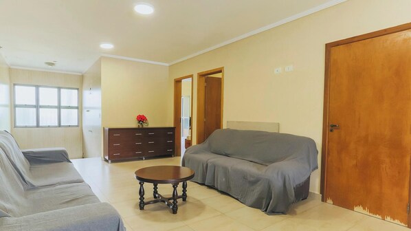A living room with a sofa, a round wooden coffee table, a cabinet, and a door.