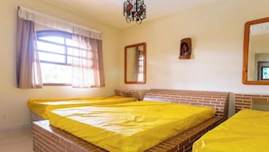 Una habitación con dos camas, una ventana con cortinas, un candelabro y un espejo en la pared.