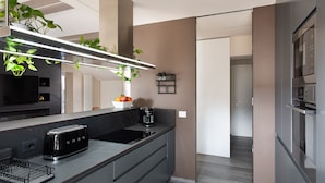Una cocina moderna con tostadora integrada, cafetera y una planta en la encimera.