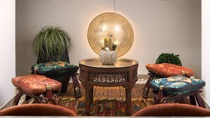 Un espacio interior acogedor con techo alto, un aplique decorativo y una pequeña mesa con una planta y un adorno.