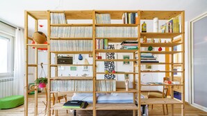 Quarto com estante de madeira contendo livros e objetos decorativos.