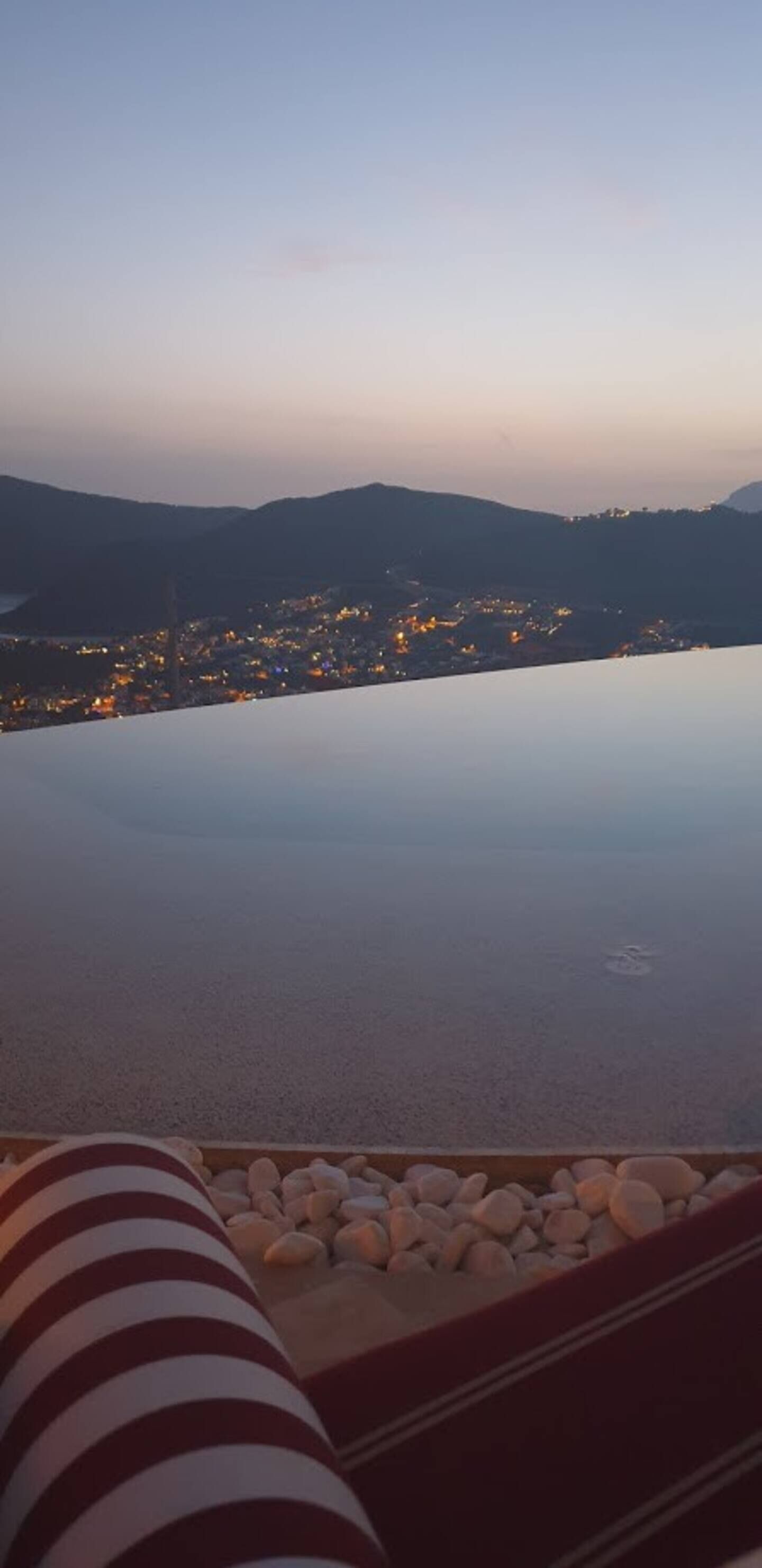 A view from an infinity pool overlooking a cityscape at dusk.