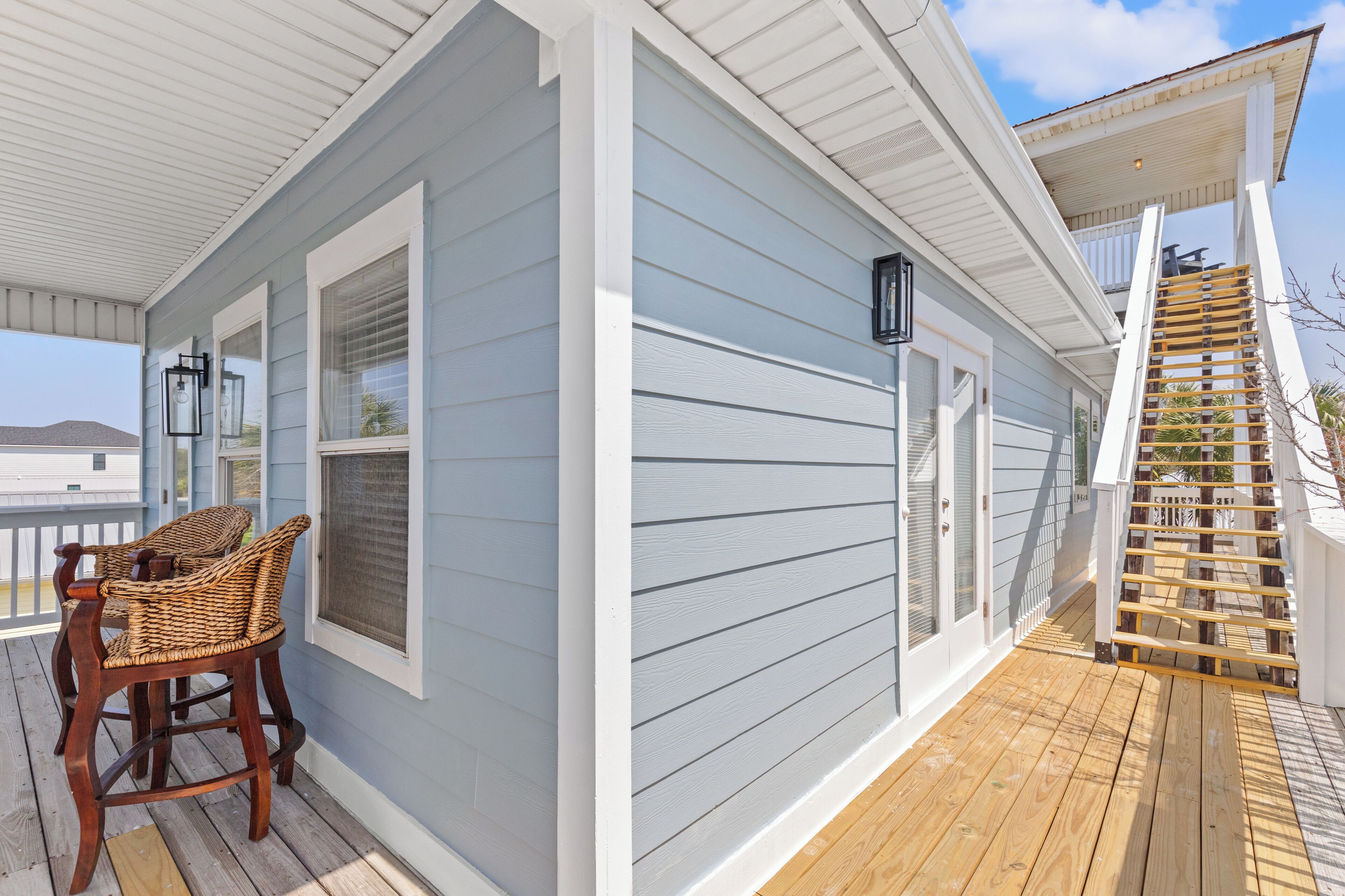 A covered porch with a wooden chair, a staircase, and a view of the ocean.