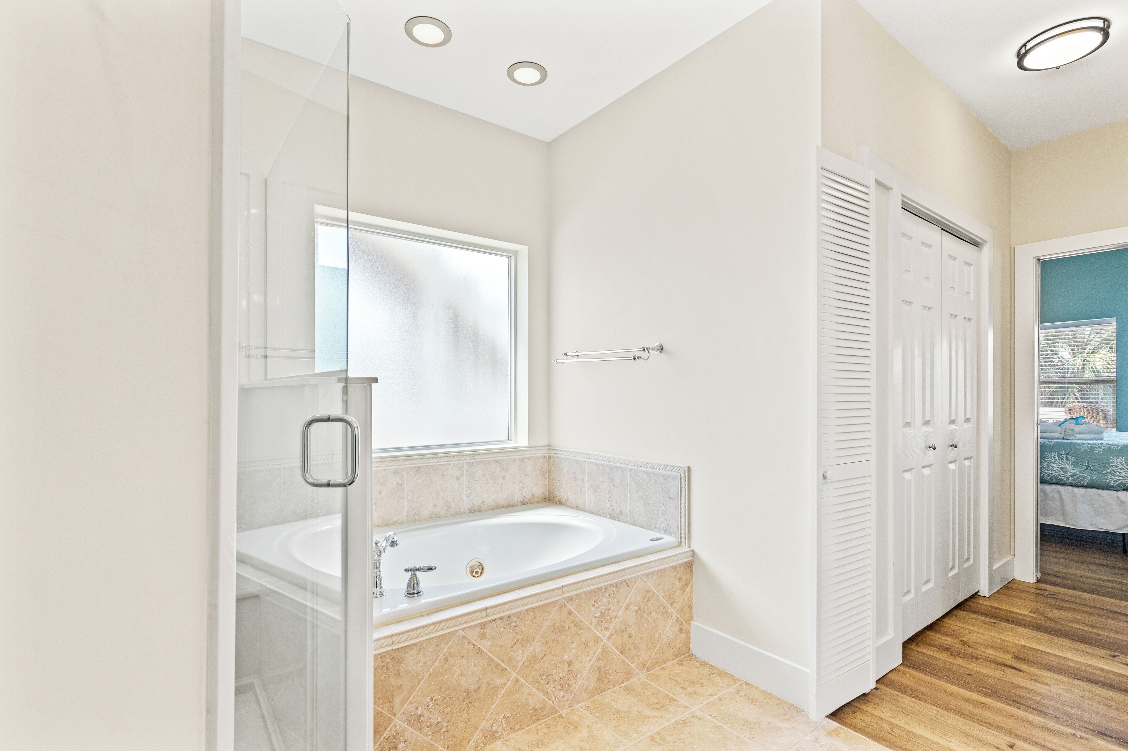 A modern bathroom with a glass shower enclosure, a freestanding bathtub, and a large mirror.