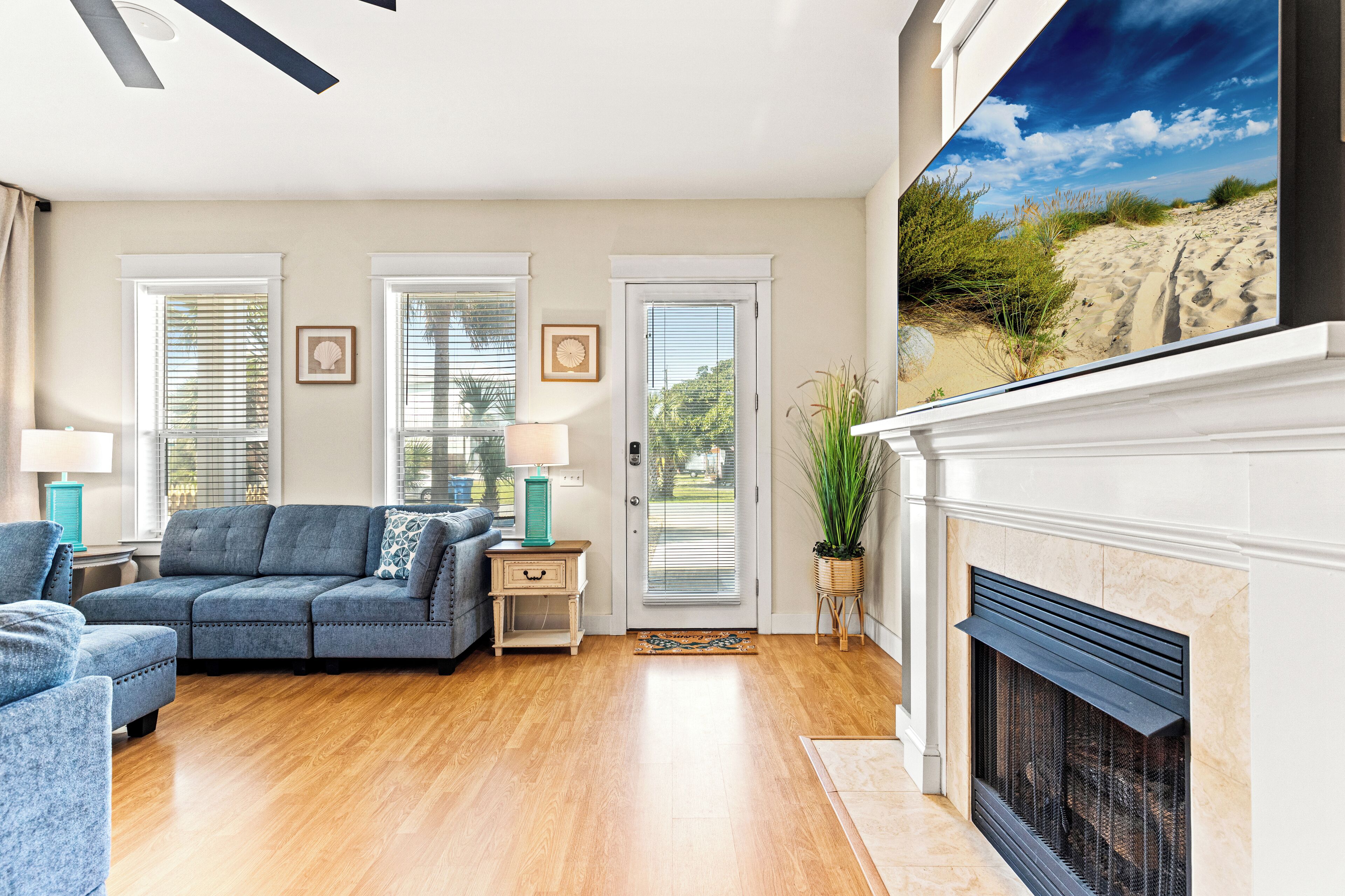 A living room with a fireplace, a sofa, a coffee table, and a large window with a beach view.