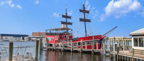 A red ship docked at a pier with a clear sky and calm water.