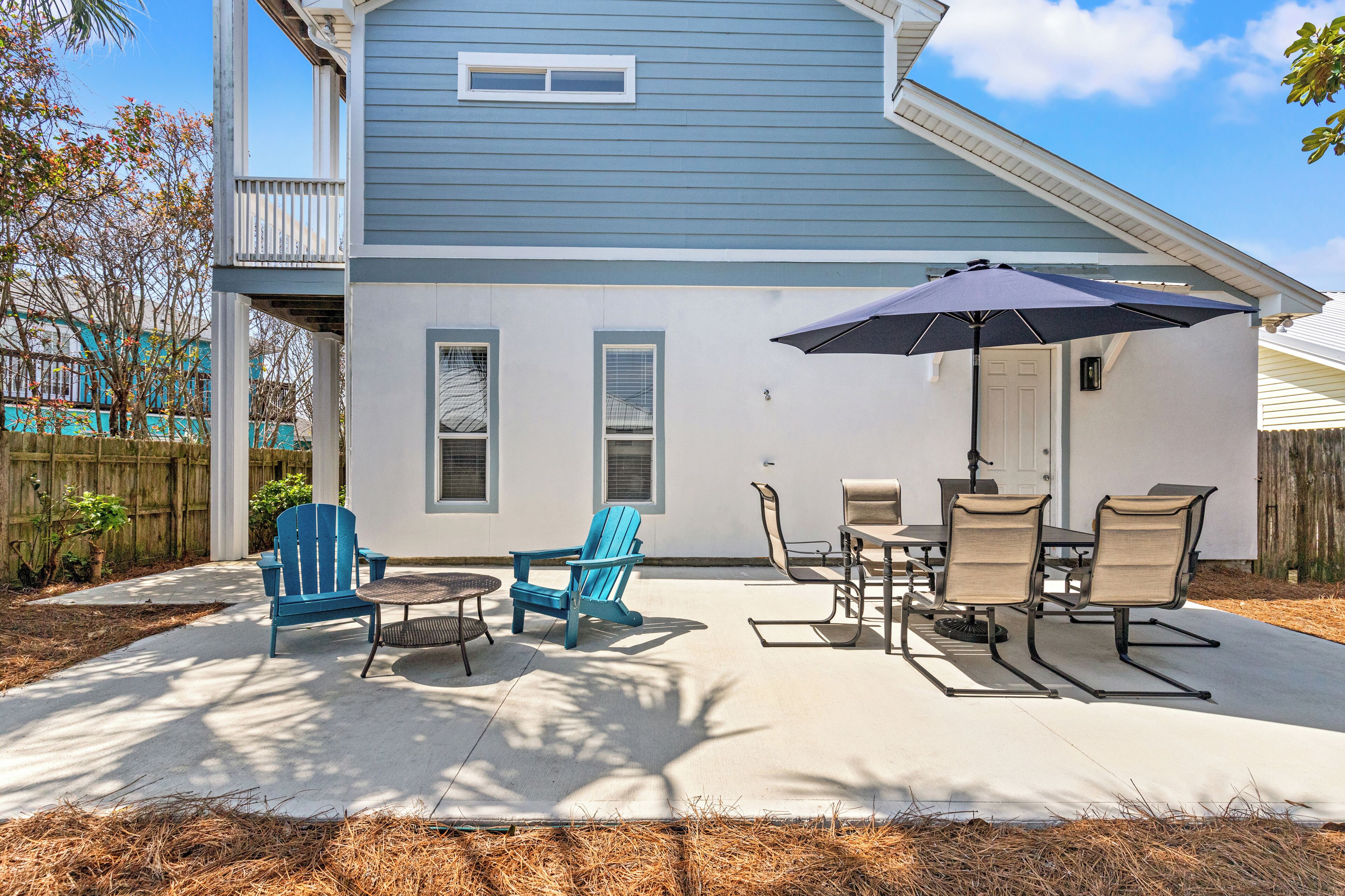 A house with a covered patio, outdoor seating, and a large umbrella.